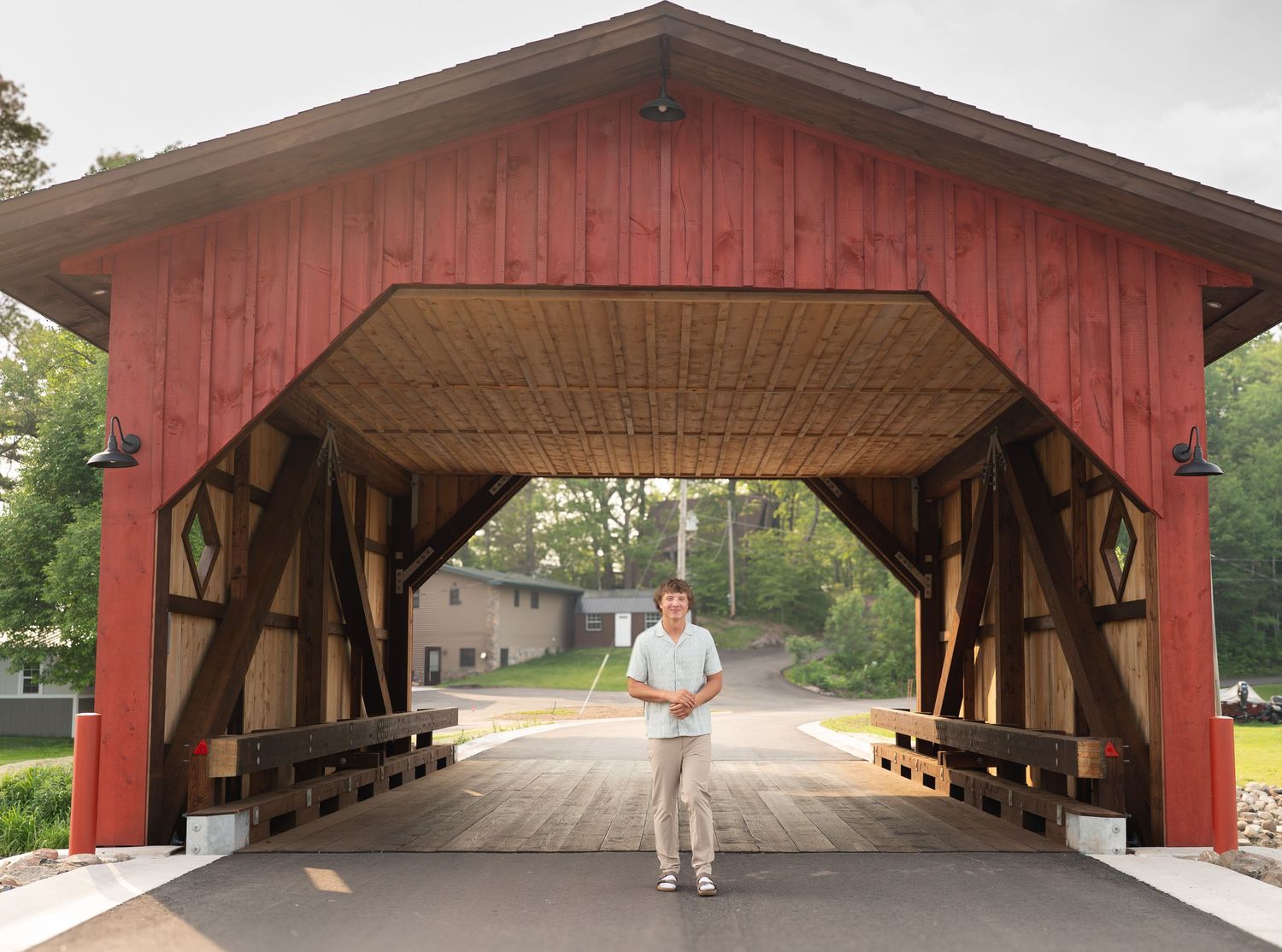 Panoramic view of a red covered bridge with sunlight streaming through showing a person walking.