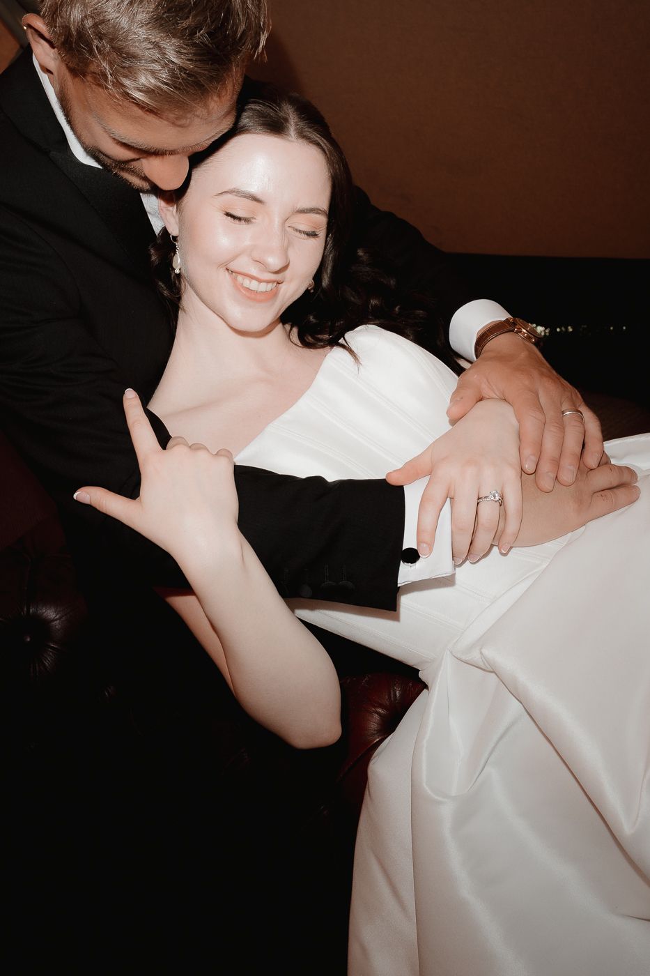 Someone wearing a white gown performs sign language during what appears to be a wedding or formal event.