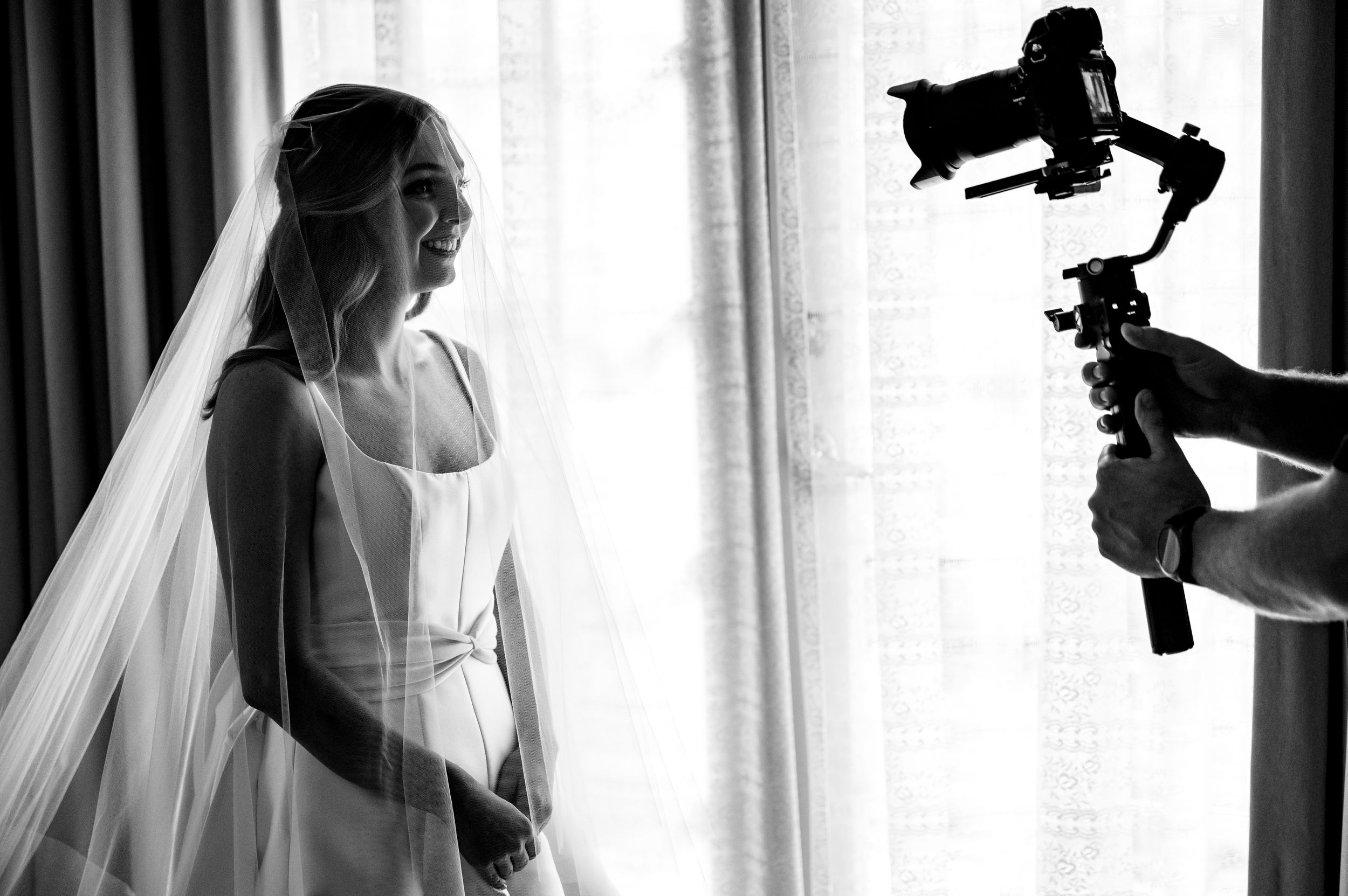 A black and white image showing wedding photography in progress with camera equipment visible.