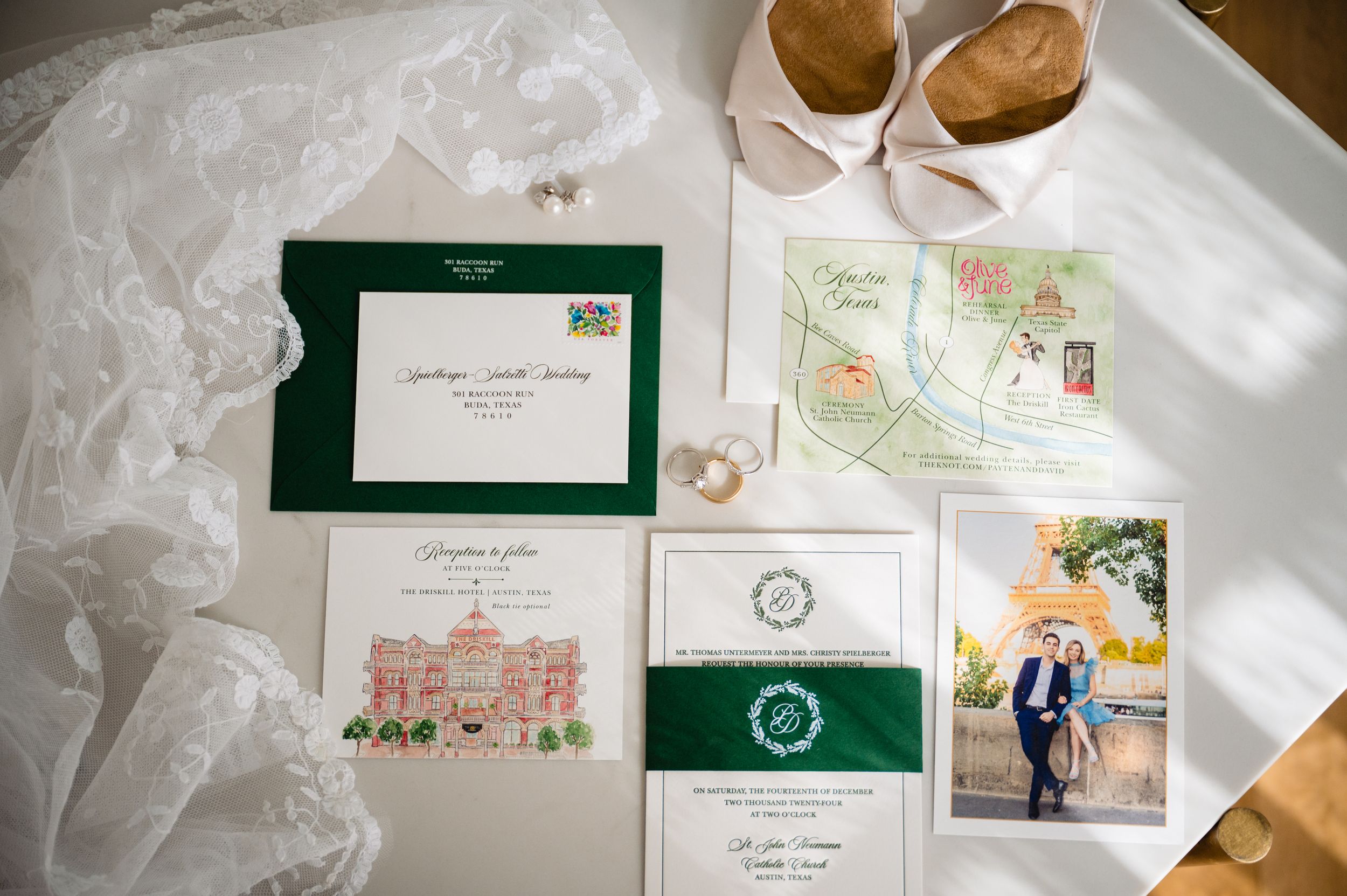 Wedding stationery suite featuring elegant green and white invitations with floral designs and envelopes laid out on white surface.