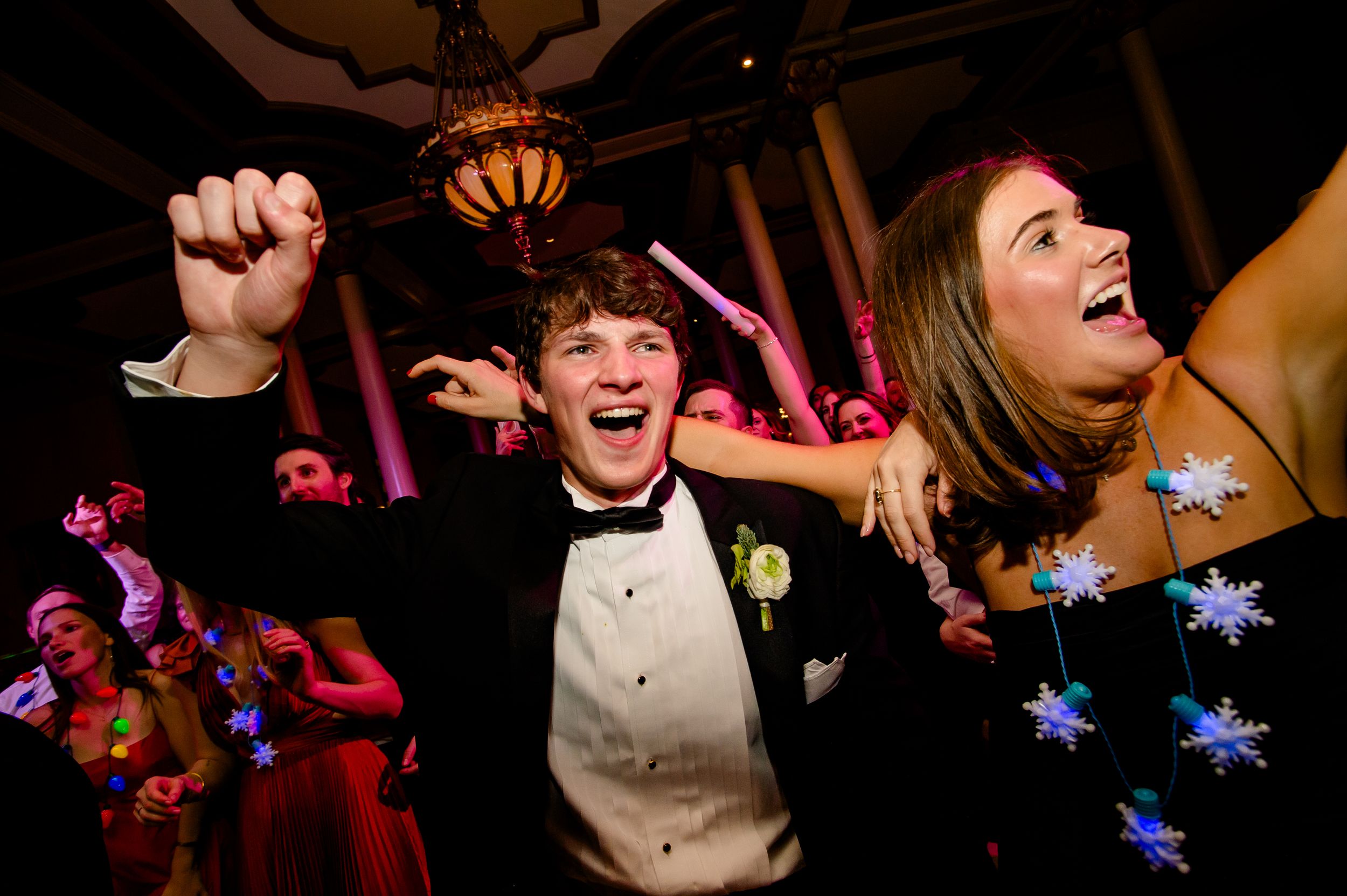Guests dancing and celebrating at a wedding reception with colorful lighting and high energy on the dance floor.