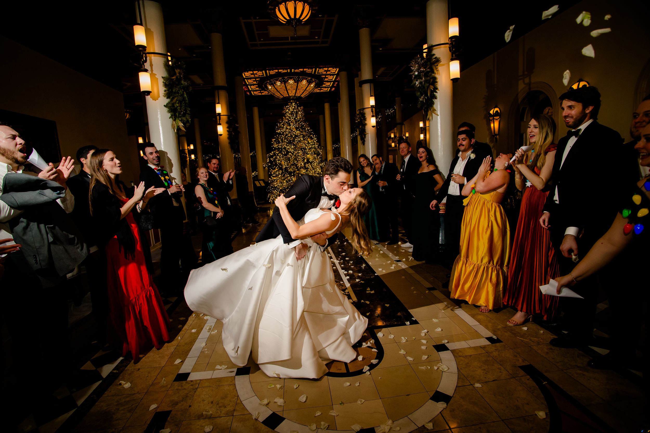 Wedding guests dancing and celebrating on the dance floor during a dimly lit evening reception.