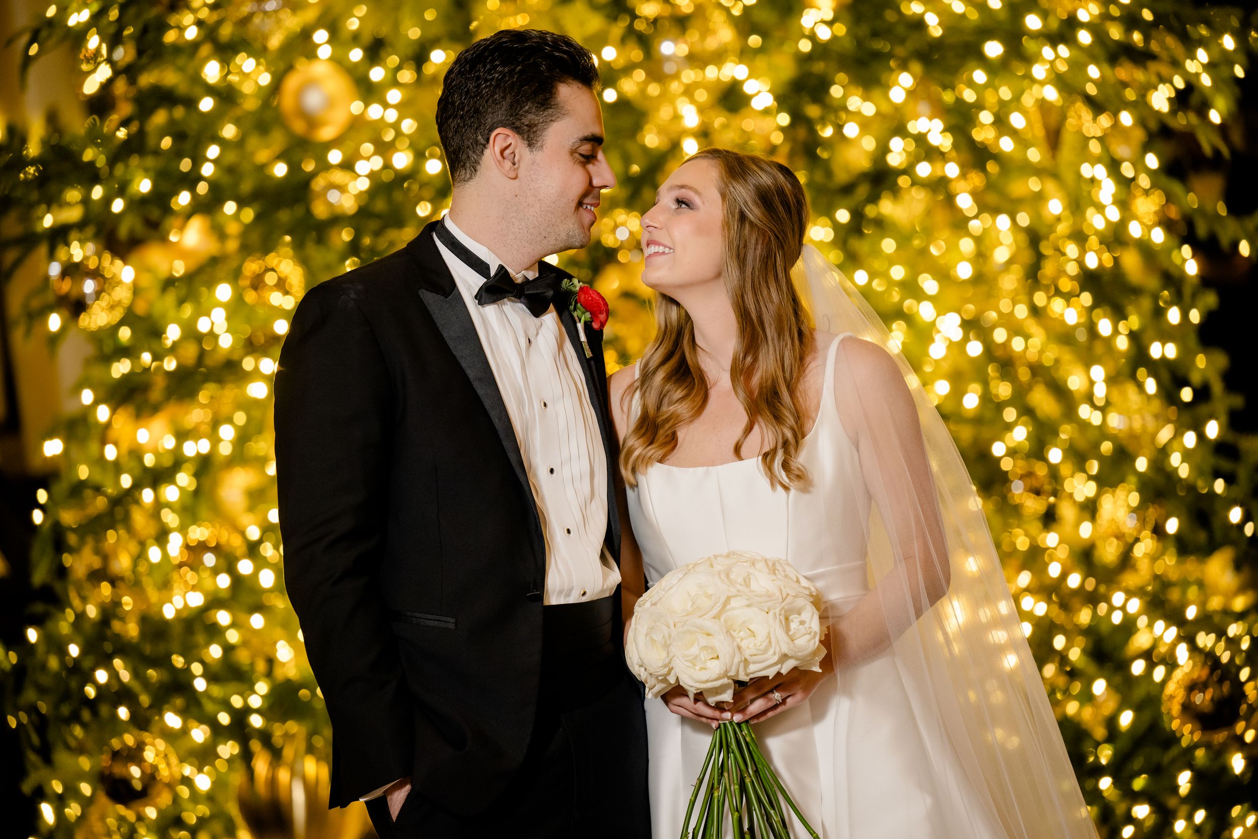 A couple shares intimate moments at their wedding reception with twinkling golden lights creating a romantic backdrop.