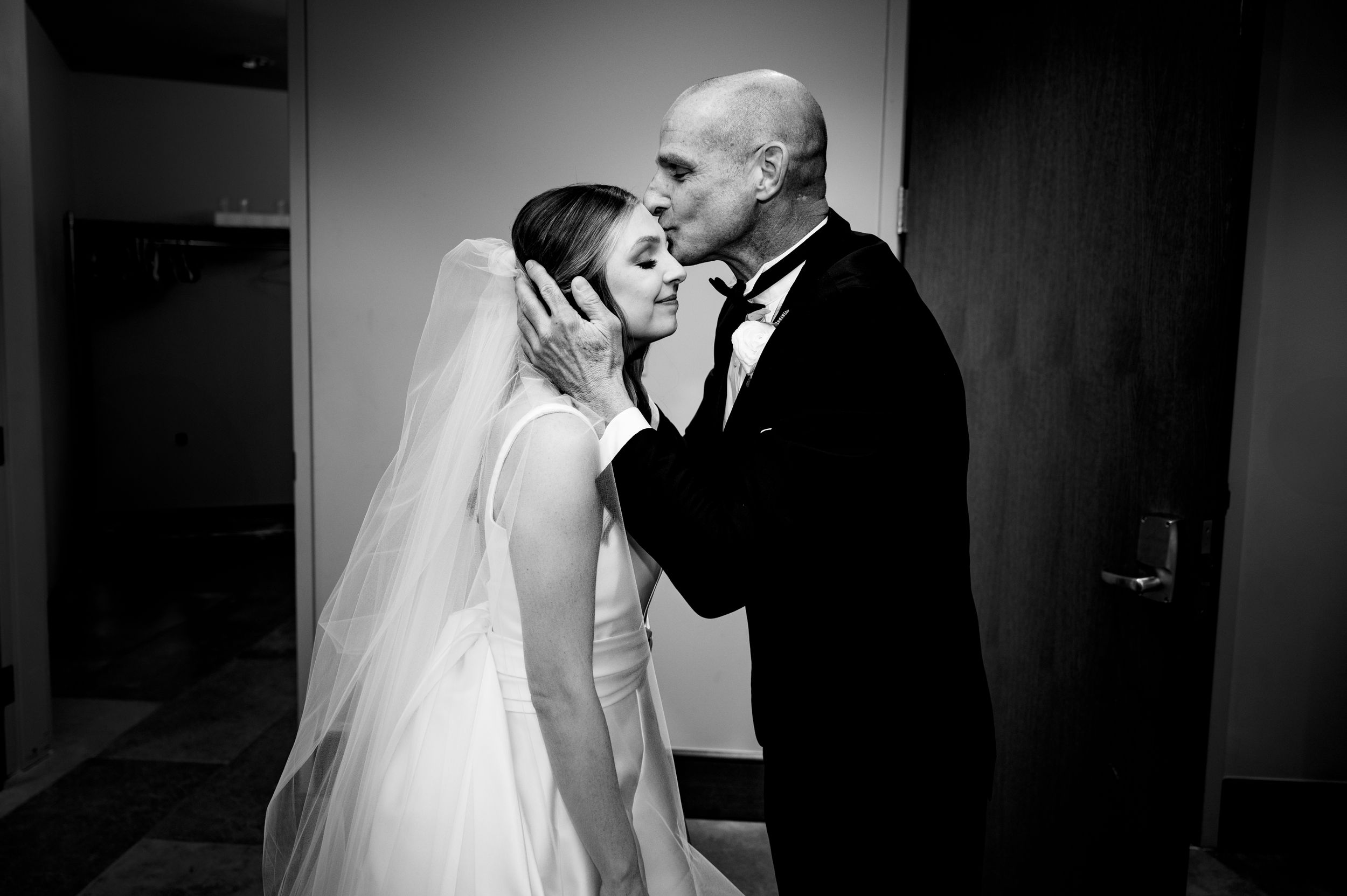A tender moment captured in black and white between two people during a wedding celebration.