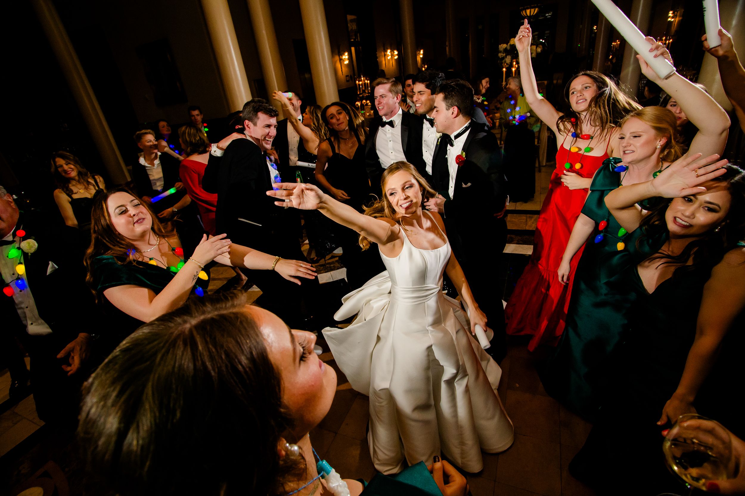Wedding guests dancing enthusiastically on a crowded dance floor during a reception celebration.