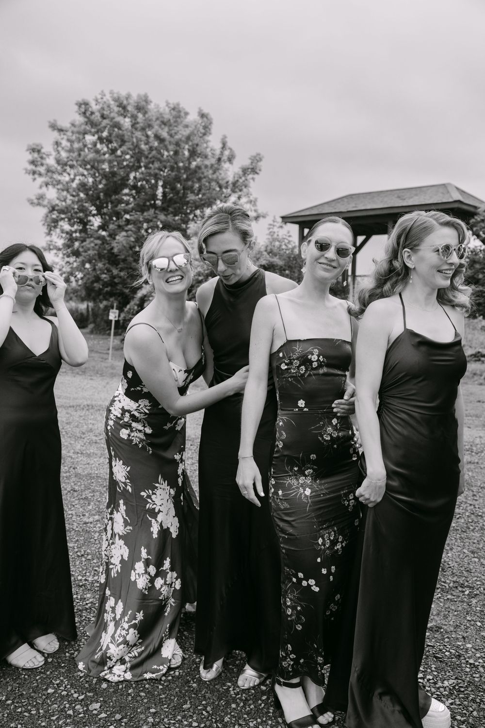 A group of people wearing formal black attire gathers outdoors for a photo in multiple poses.