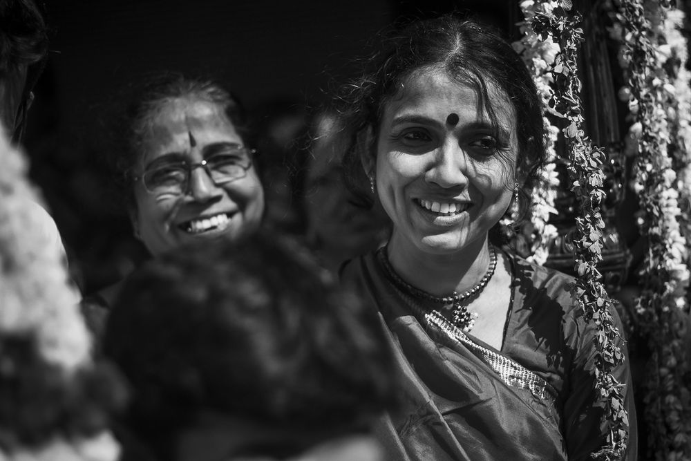 Three smiling people pose for a photo outdoors in black and white.