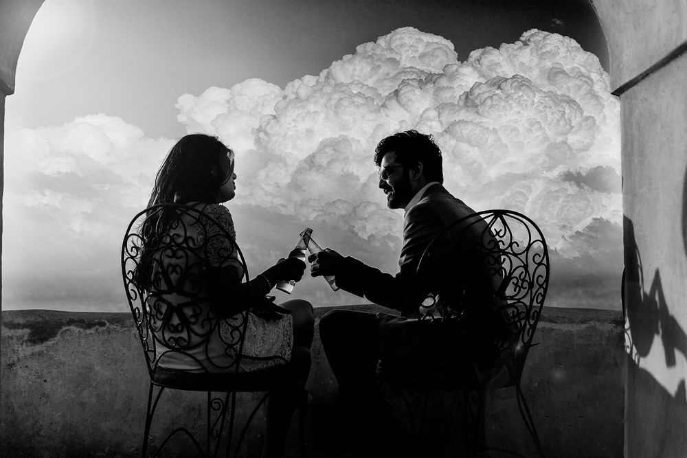 Silhouetted scene of friends enjoying a conversation while sitting in wicker chairs against a dramatic sky backdrop.