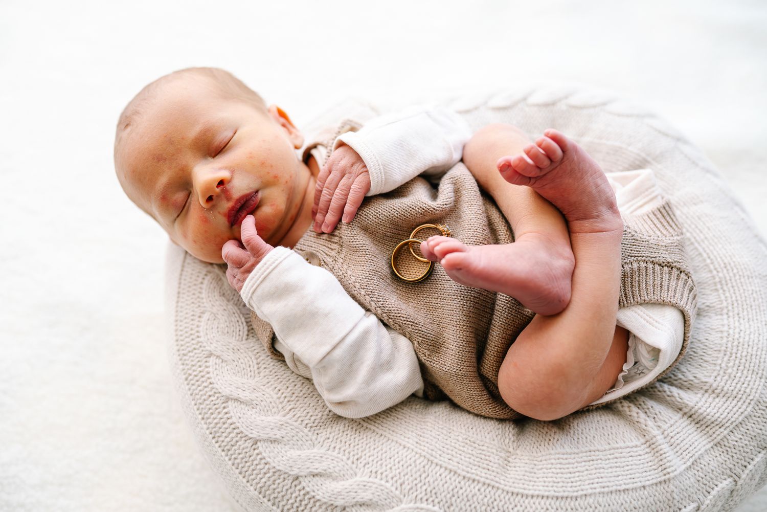 Peaceful baby sleeping on round white pillow wearing neutral clothing in minimalist setting taken by Melbourne newborn photographer Pei A