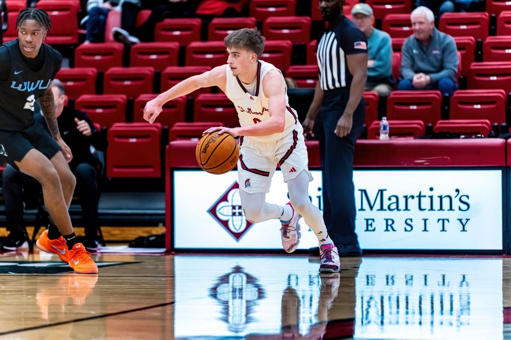 College basketball player dribbling on court at Saint Martin's University during a competitive game.
