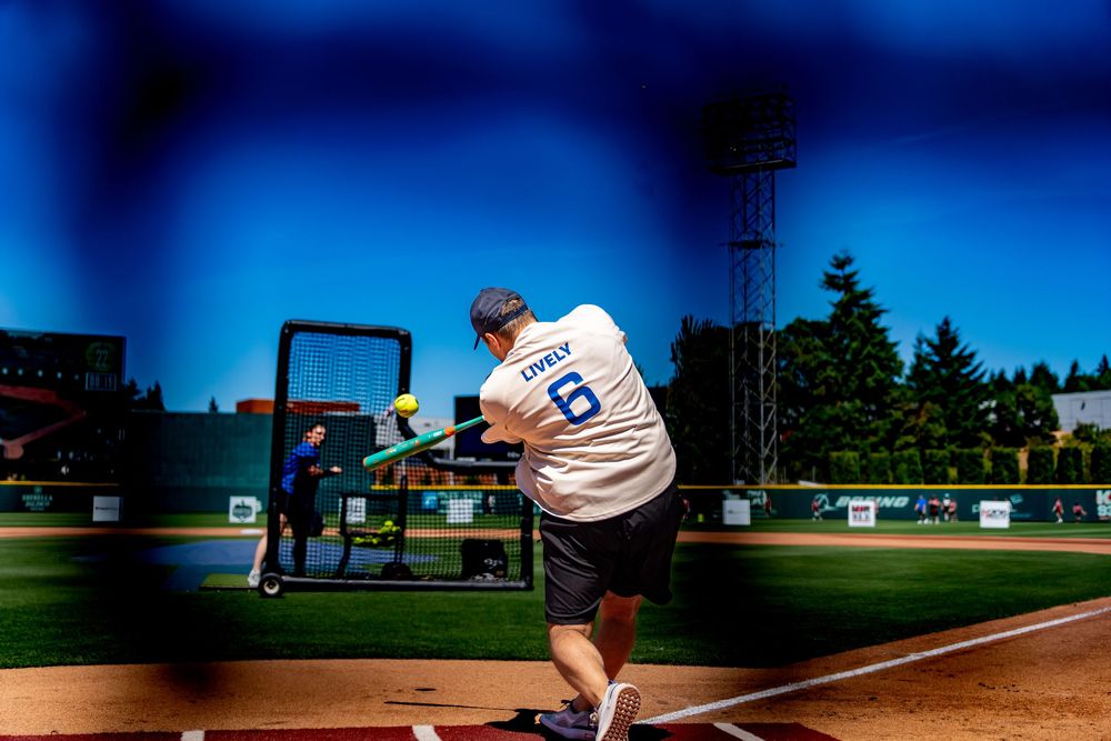 Batter swinging at a pitch during a baseball game on a sunny day at an outdoor ballpark.