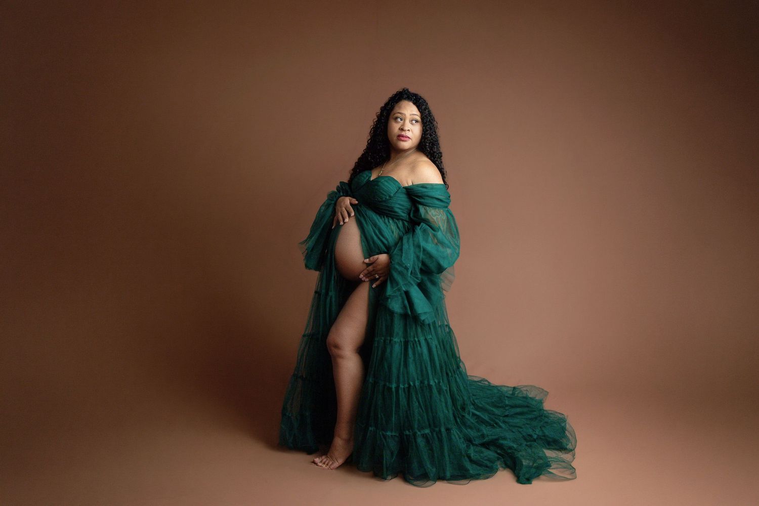 Elegant emerald green tulle gown with sweetheart neckline and flowing long sleeves displayed on a mannequin.