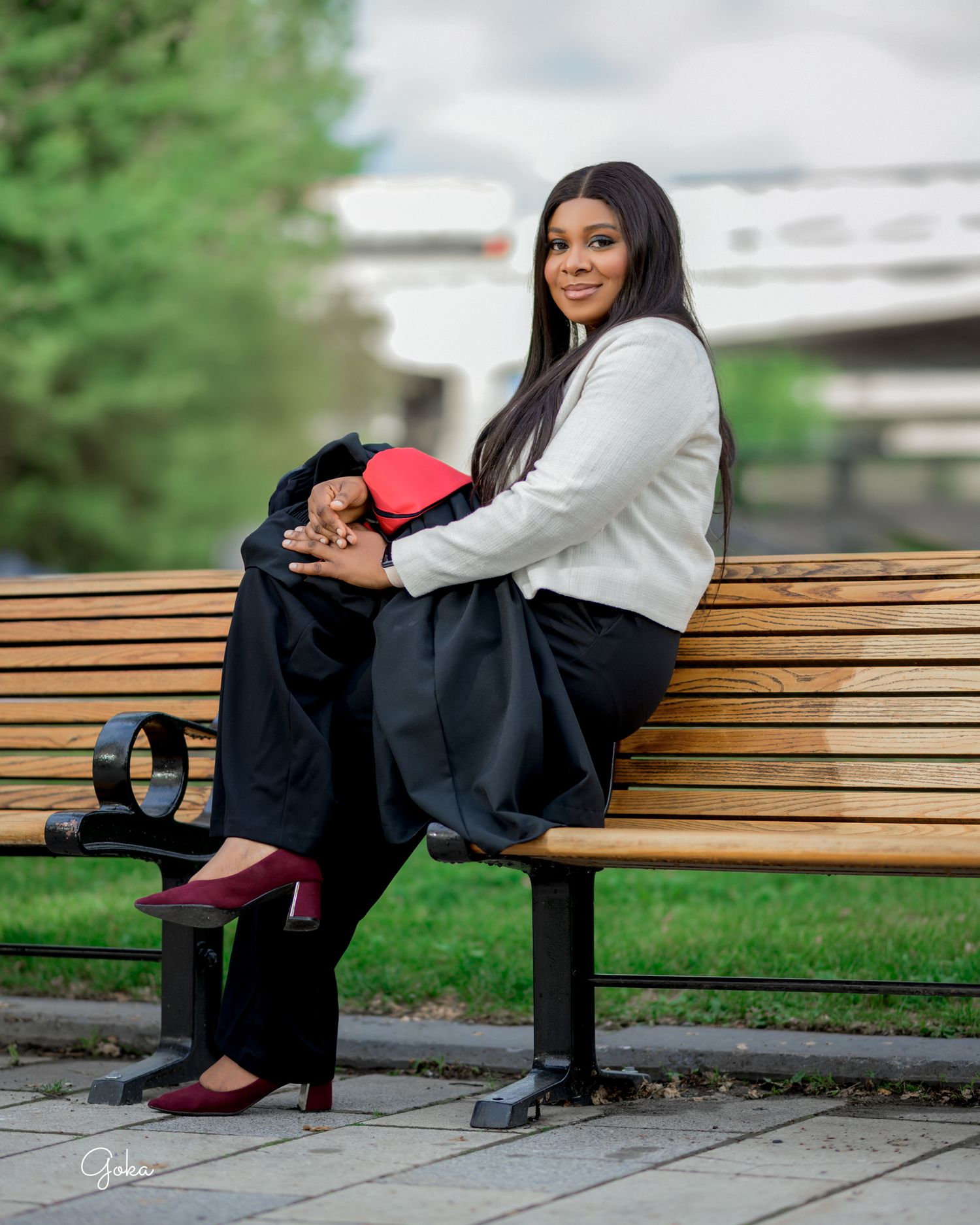 Professional senior portrait session in a outdoor park setting featuring poses on a wooden bench.
