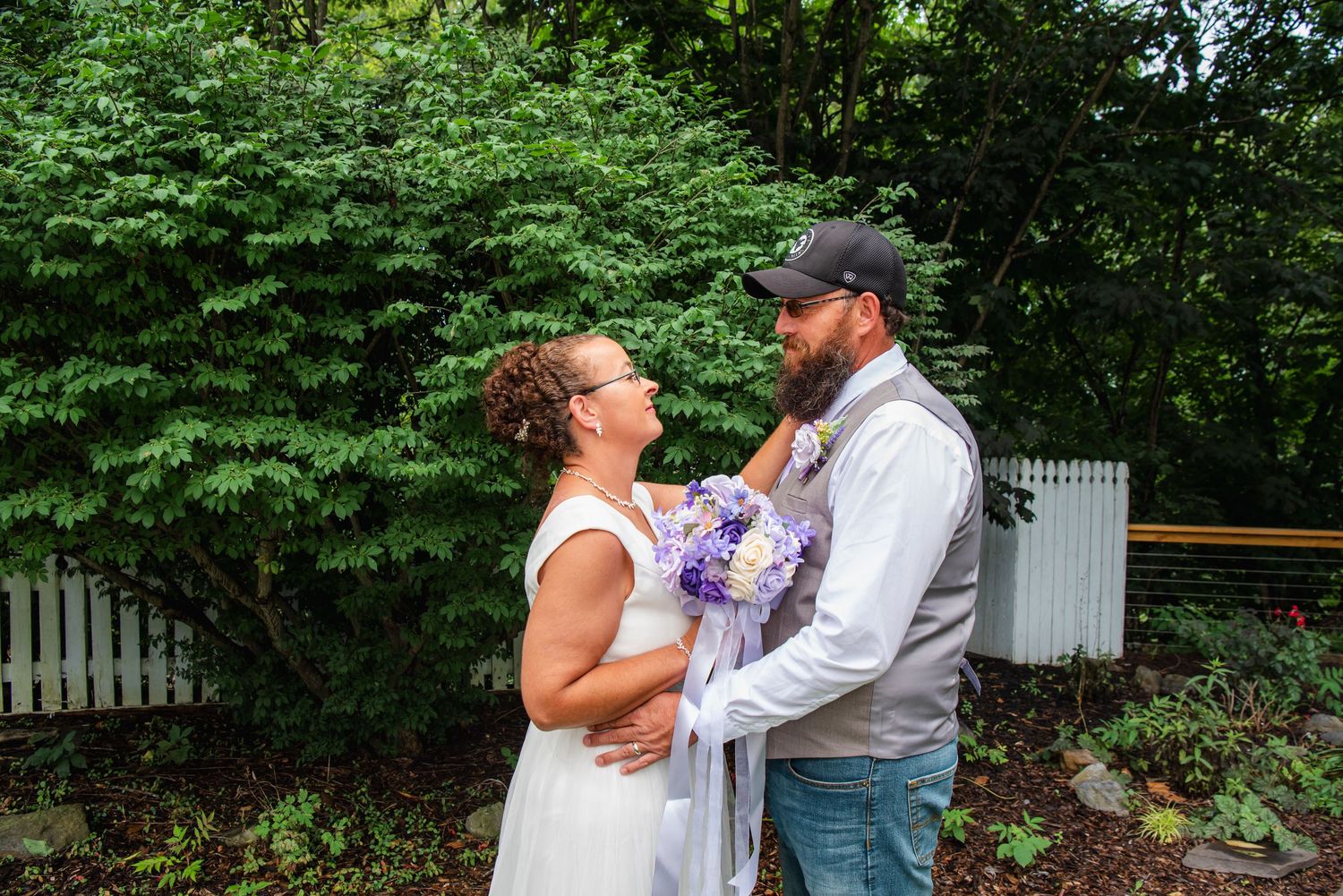 Wedding couple embracing in front of a white garden gazebo during an outdoor ceremony at the Appalachian Wedding Chapel.