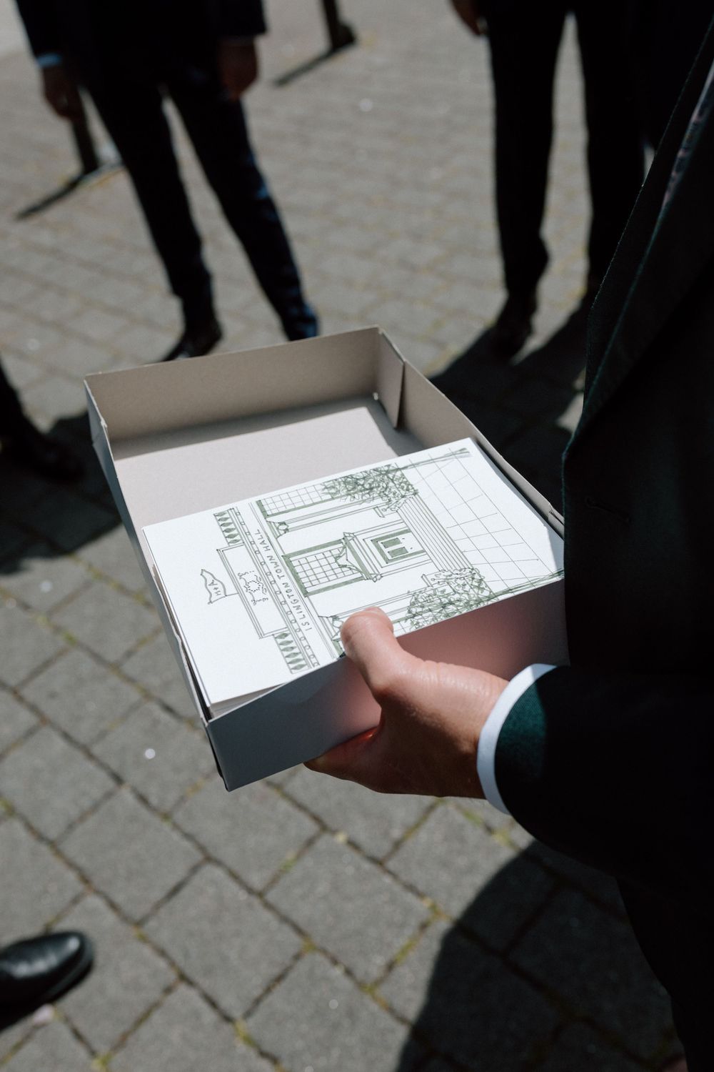A groomsman holds order of services for Islington Town Hall wedding.