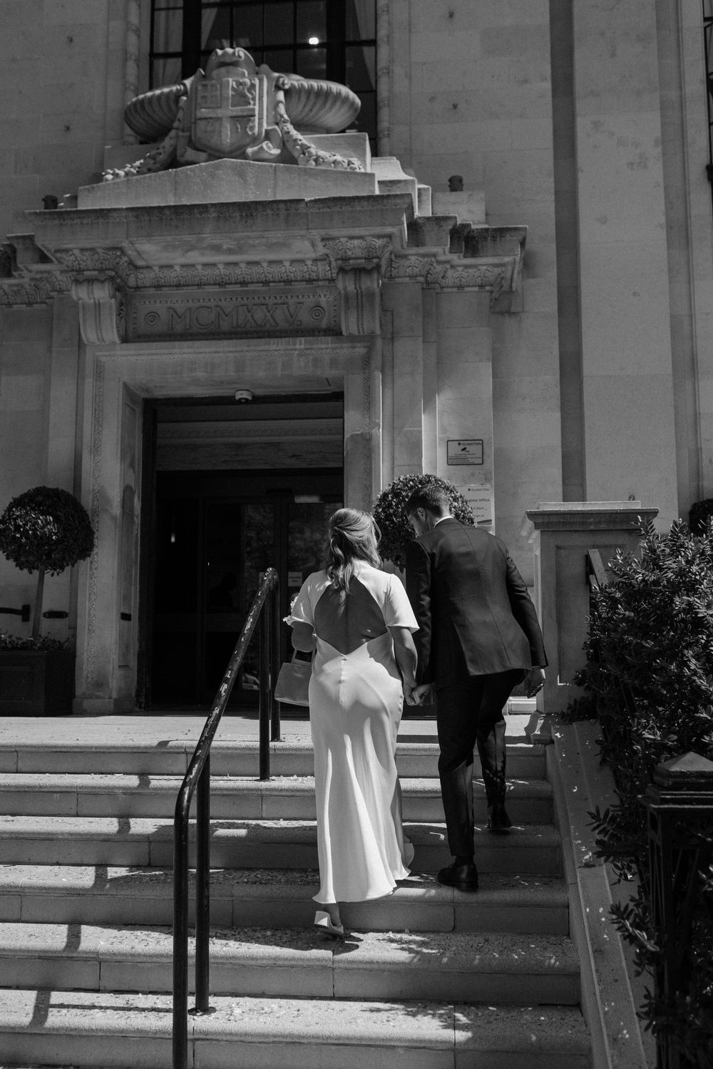 A couple enters Islington Town Hall with ornate architecture through steps leading to a doorway with decorative stonework.