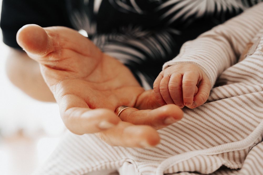 Hände von Vater und Baby halten sich