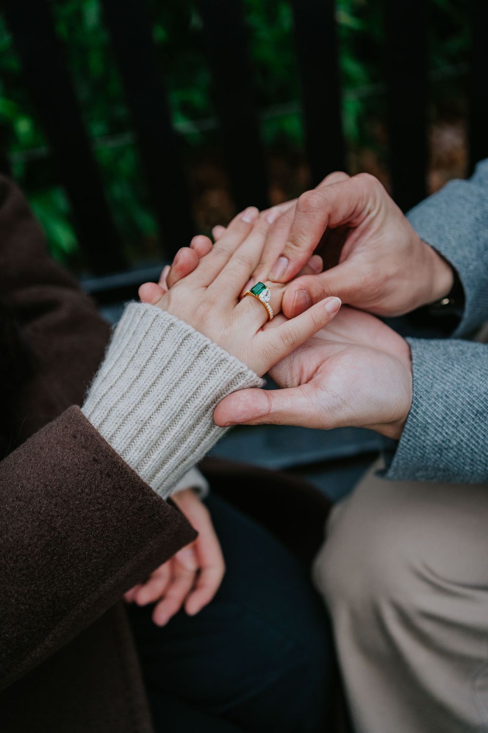 Close-up shot of hands placing an engagement ring with turquoise stone during romantic outdoor proposal moment.