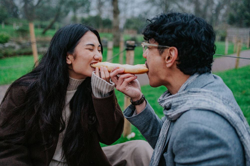 A joyful couple sharing playful moments and laughter while walking in a garden setting.