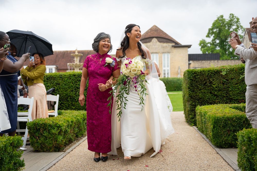 Joyful moment at an elegant outdoor wedding ceremony with guests celebrating on a manicured garden path by a chateau.
