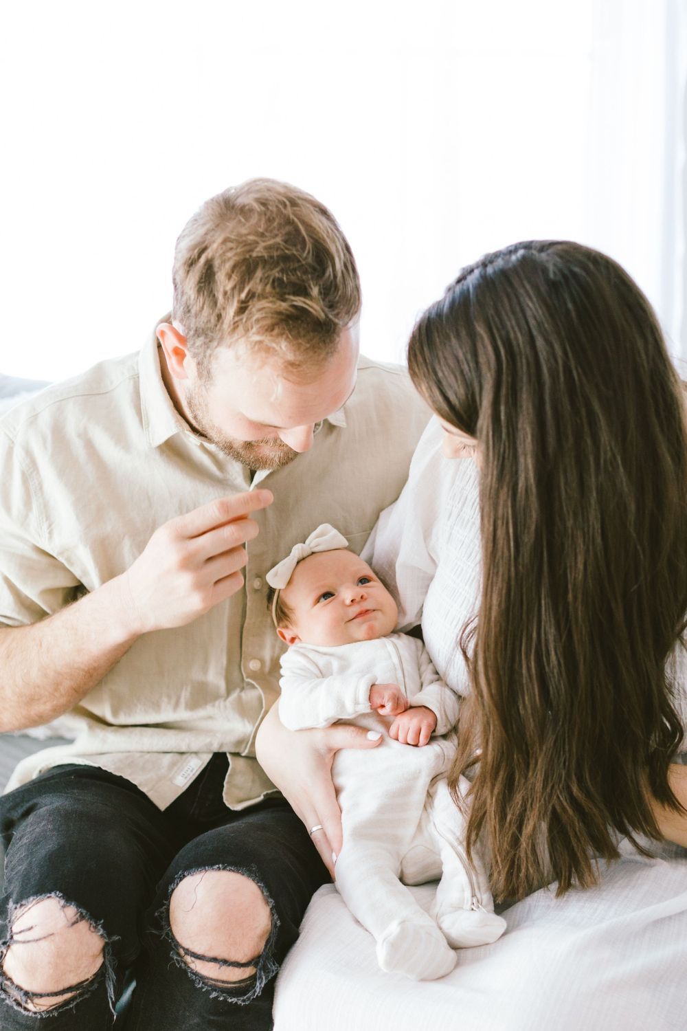 Family sharing joyful moment with baby wearing white onesie.
