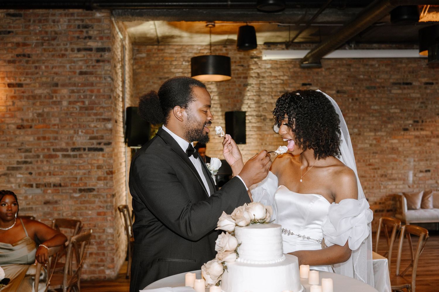 Wedding couple shares cake at rustic brick venue in playful sequence of cake smashing photos.