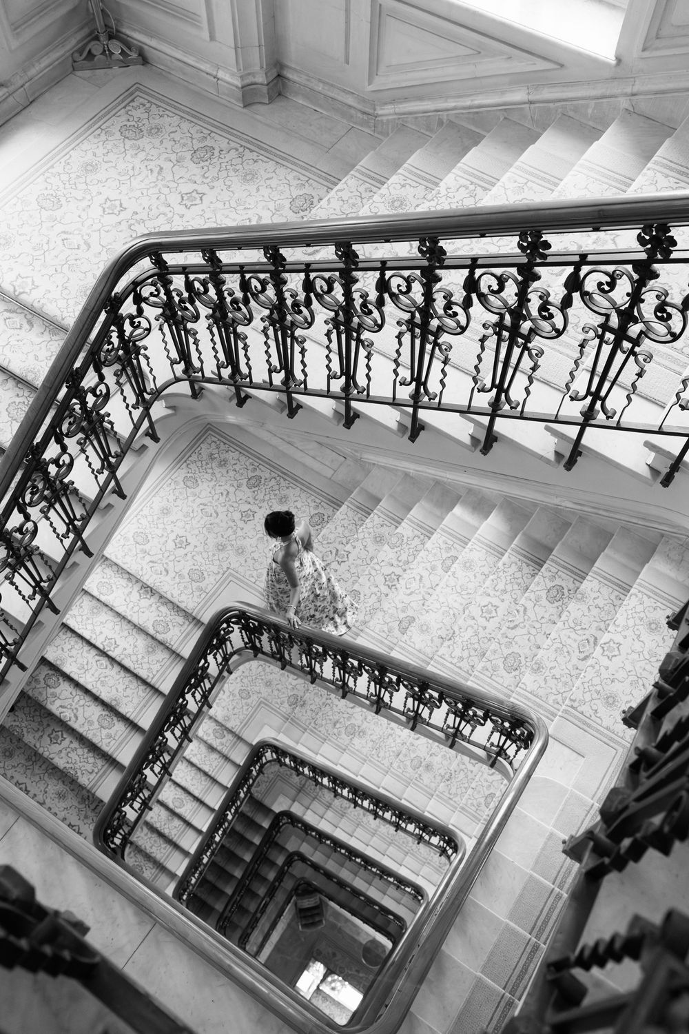 Grand marble staircase with decorative black metal balustrade viewed from above in black and white.