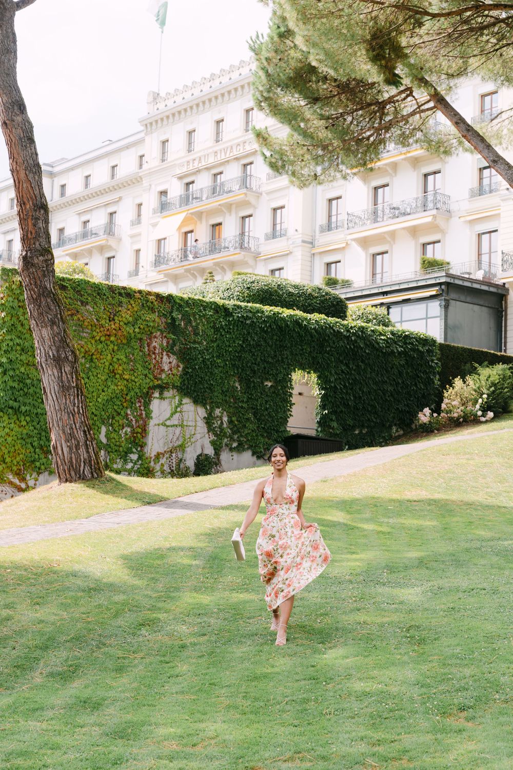 A beautiful historic building with elegant architecture sits atop a manicured green lawn in summer.