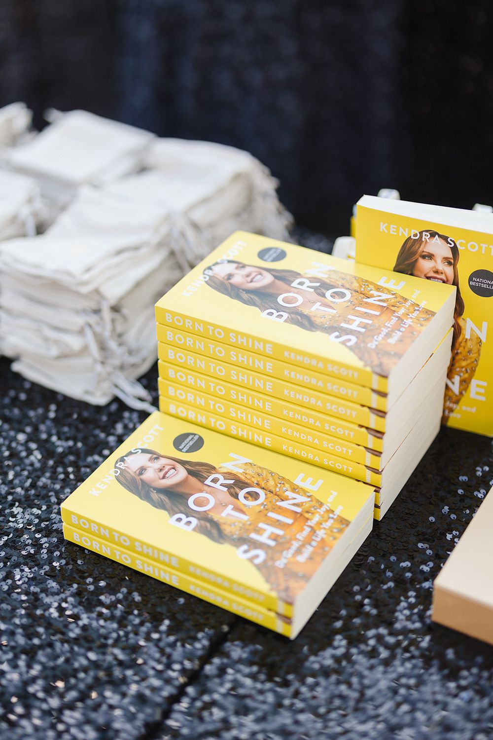 Stack of yellow inspirational books displayed on sparkly dark surface.