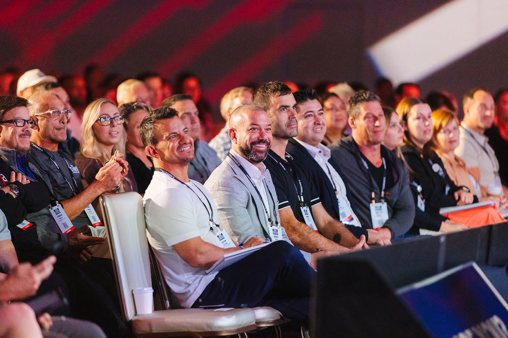 Large audience sits attentively in rows at a business conference or corporate presentation event.
