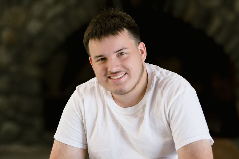 A person wearing a white t-shirt poses for a series of headshots with different expressions against a dark background.