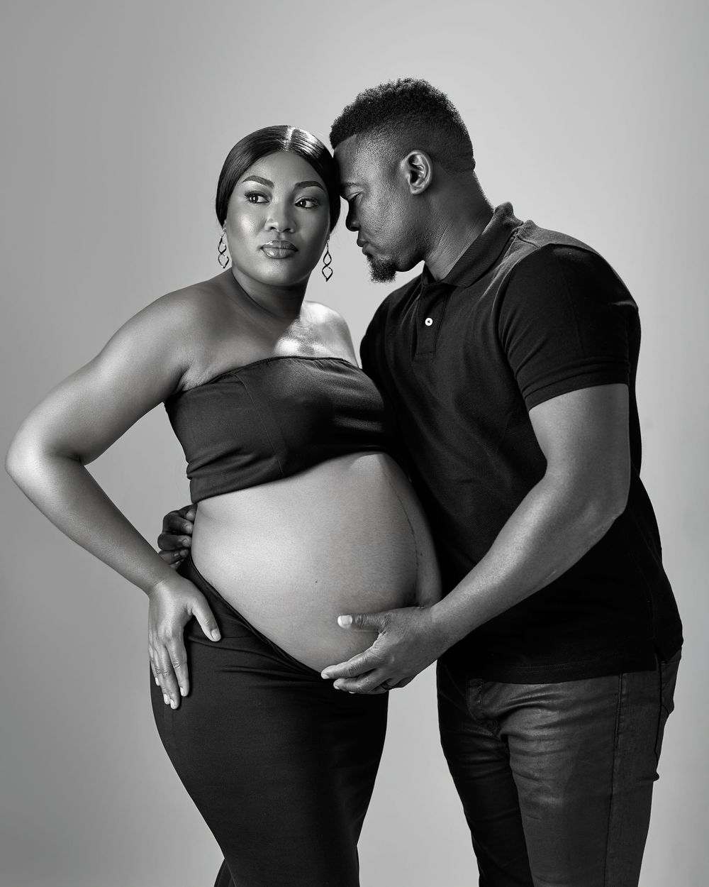 A couple standing for a maternity shoot in black and white