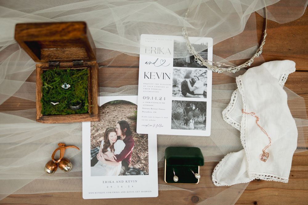 Wedding details flatlay with invitation, rings in moss box, and vintage styling elements.