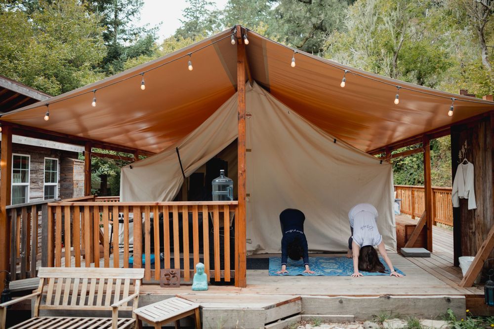 Glamping-style wedding venue with white tent, wooden deck and string lights.