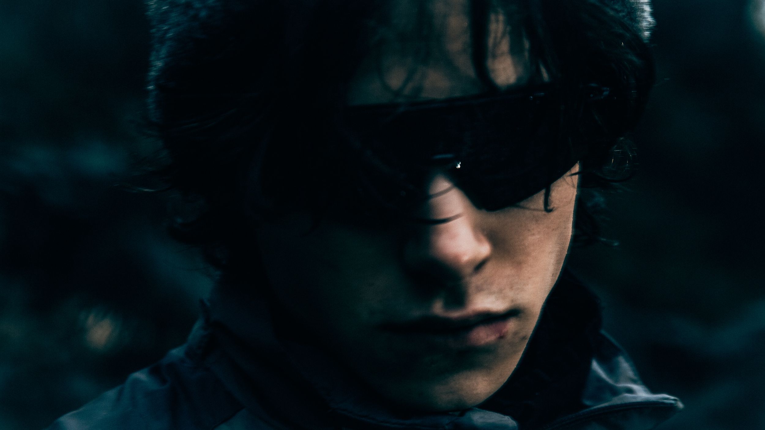 Dramatic portrait with sunglasses against dark moody background.
