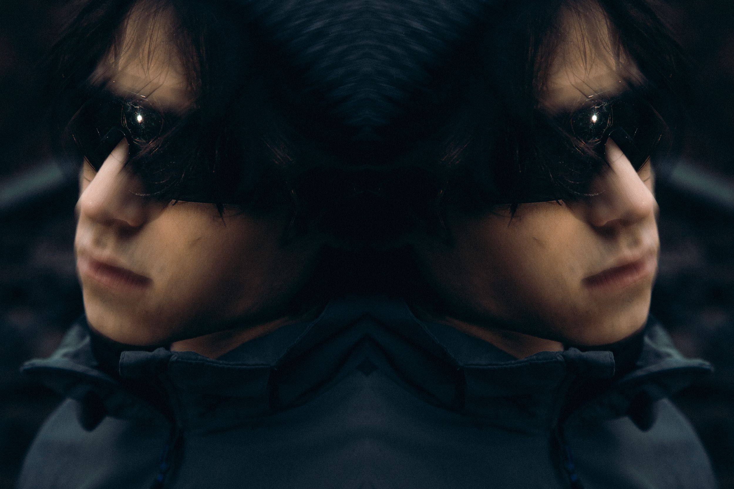 Dark artistic portrait focusing on reflective sunglasses in low light.