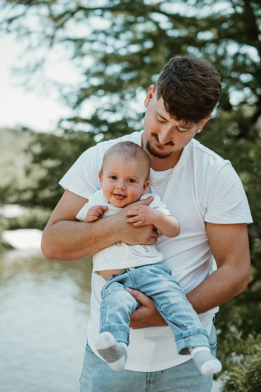 A tender moment between parent and baby wearing matching white tops and light denim.