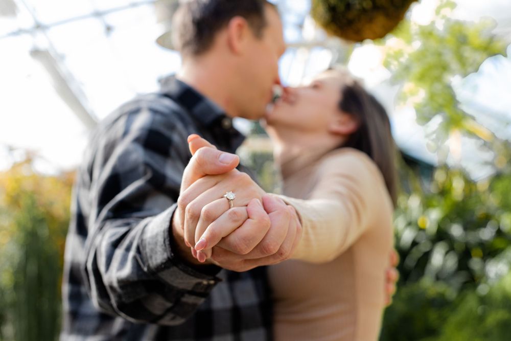Close-up of intertwined hands with engagement ring during romantic outdoor moment.