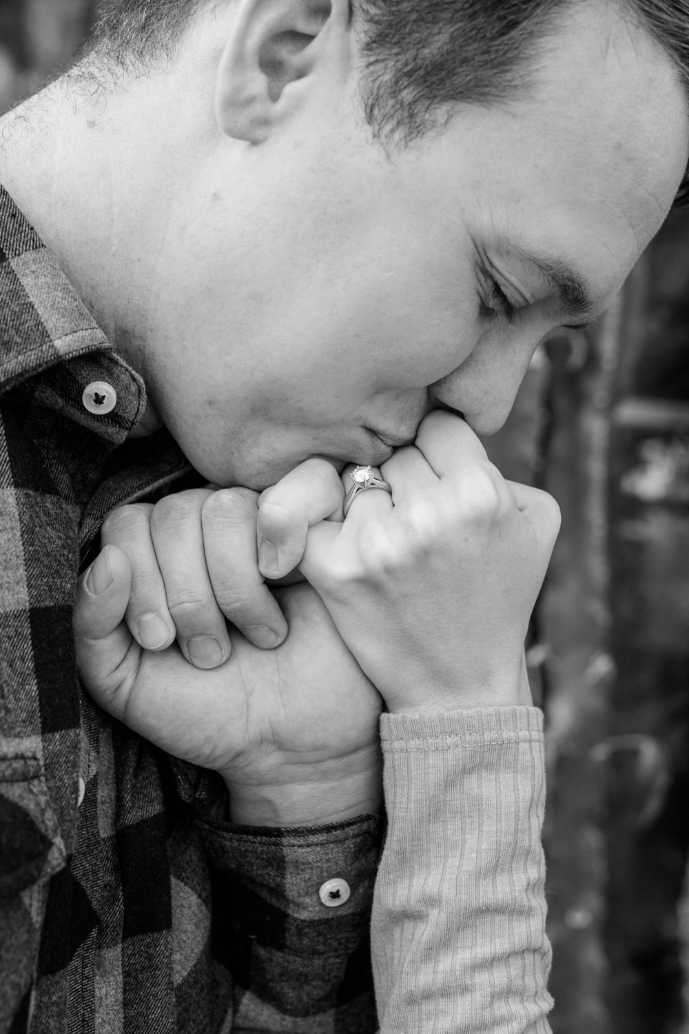 Black and white intimate portrait showing gentle kiss on clasped hands.