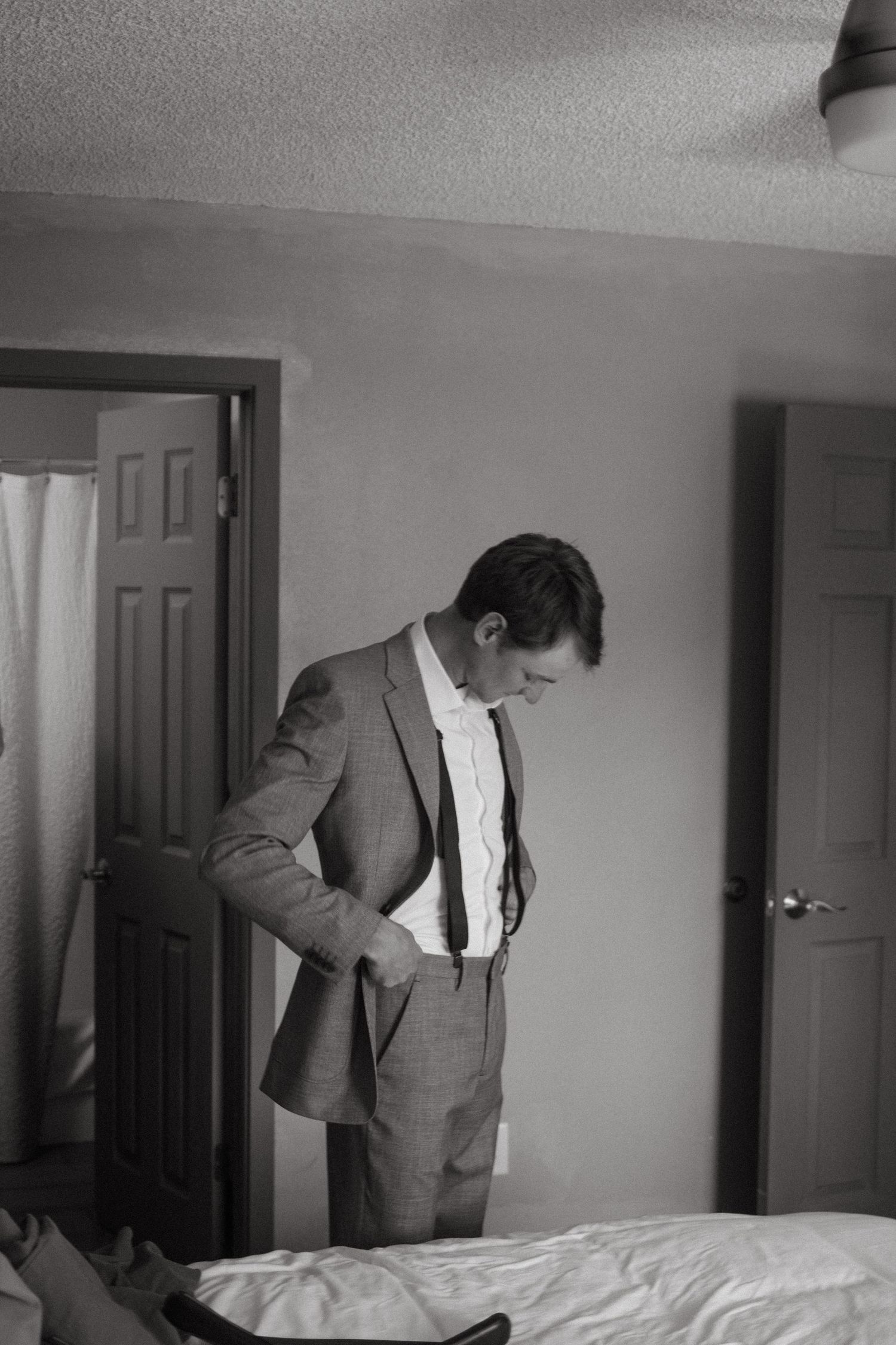 Person in a gray suit jacket getting ready in front of a white wall.