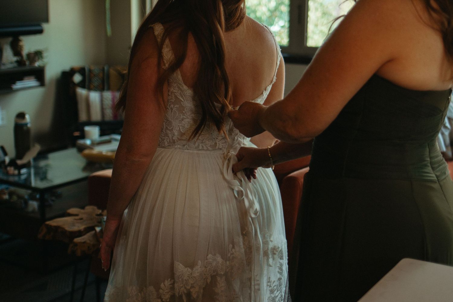 Wedding dress preparations showing delicate details being adjusted in dim lighting.