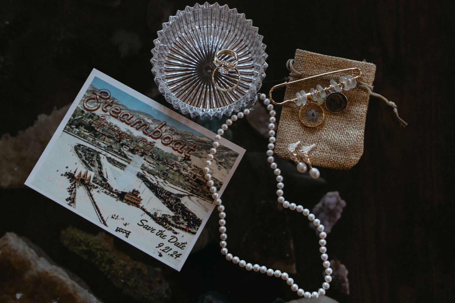 Vintage photographs and pearl necklaces arranged on dark surface.