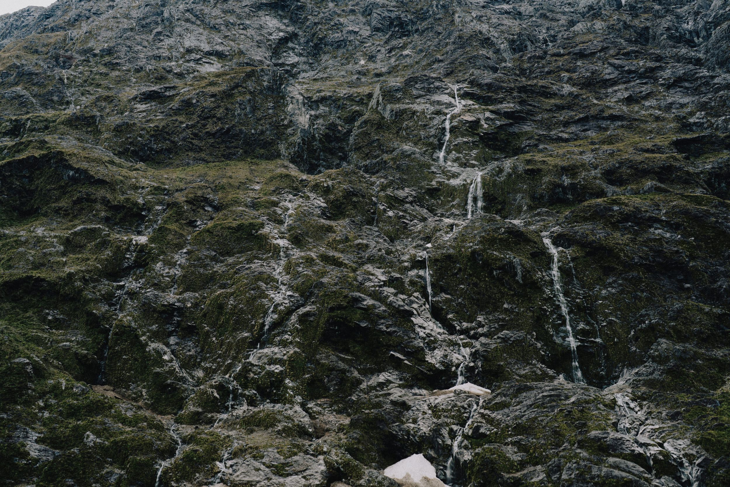 Cascading waterfalls flowing down a rocky mountain face.
