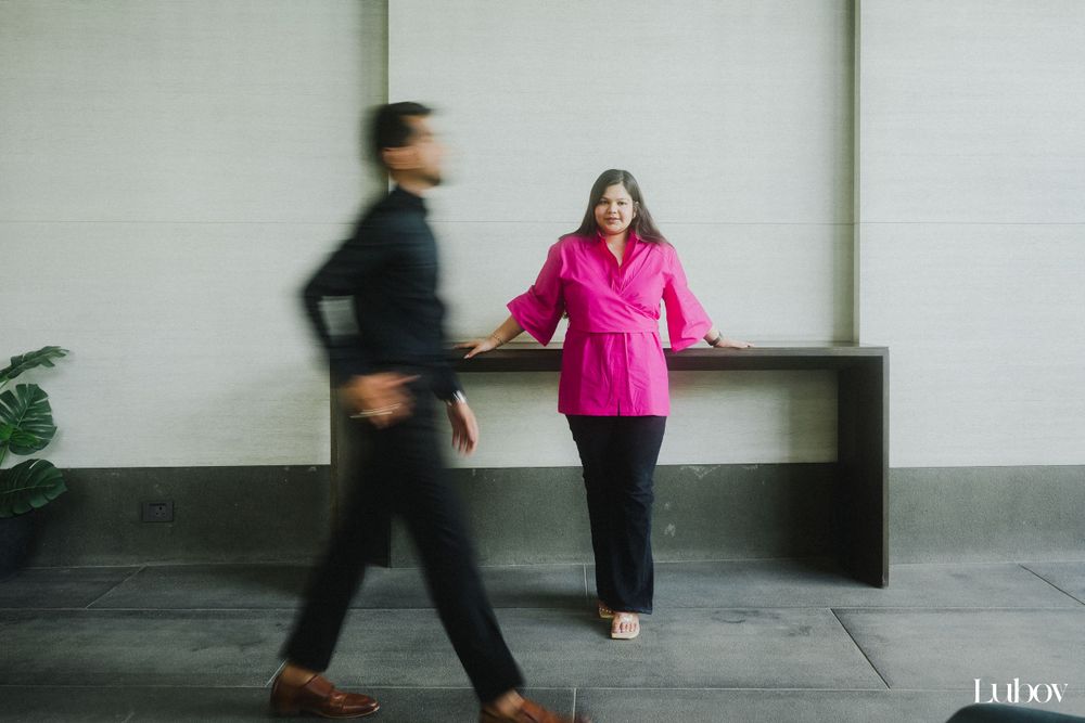Motion blur captures two people walking past each other in an industrial hallway, one wearing bright pink.