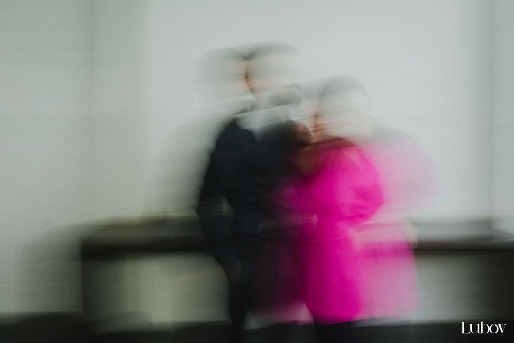 Abstract motion blur photograph showing two figures in black and pink creating an artistic effect.