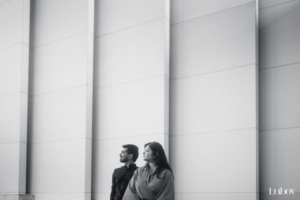 Minimalist black and white portrait against a geometric wall with vertical lines.