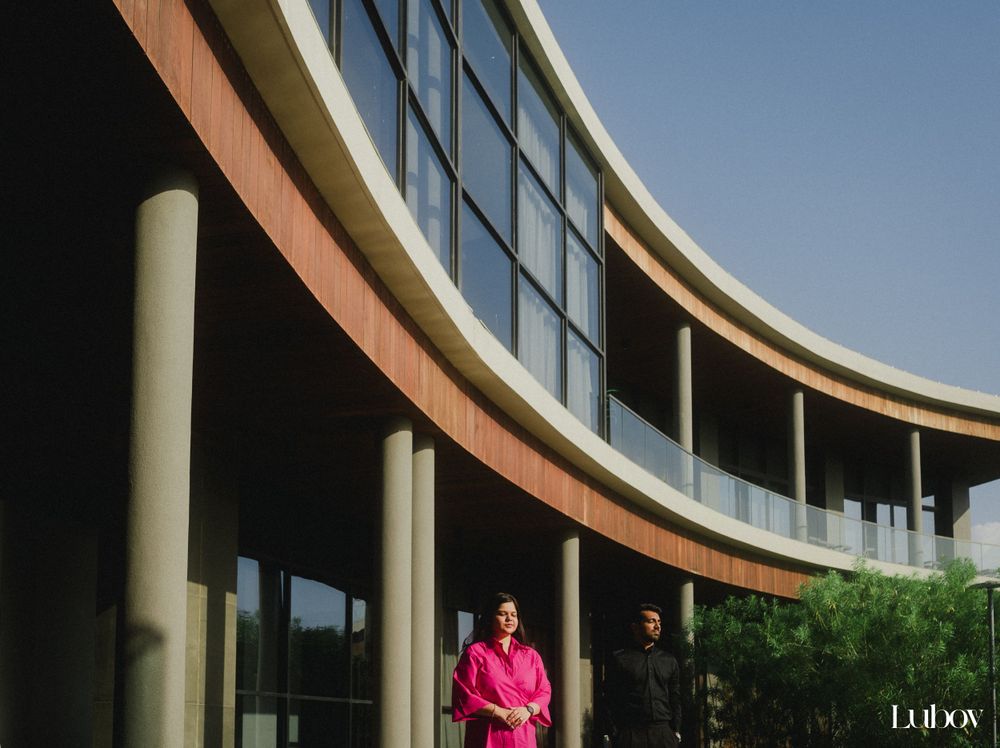 Modern curved architecture with glass windows and pillars featuring two people in contrasting outfits.
