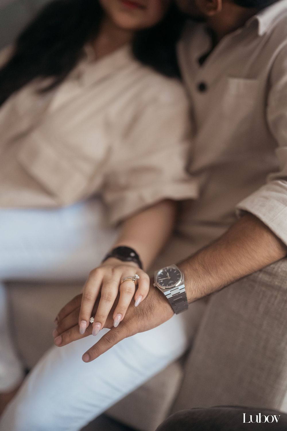 A close-up shot featuring hands with jewelry and watches in neutral tones against a soft background.