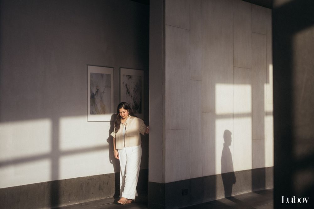 Minimalist indoor photoshoot with dramatic shadows cast on a white wall.