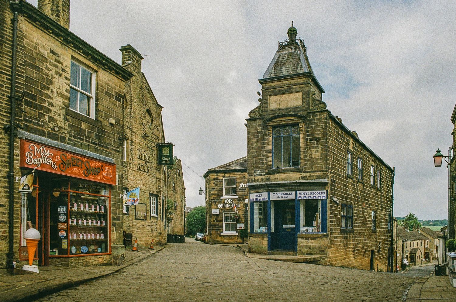 Historic stone buildings and shops on a quaint British village street corner.